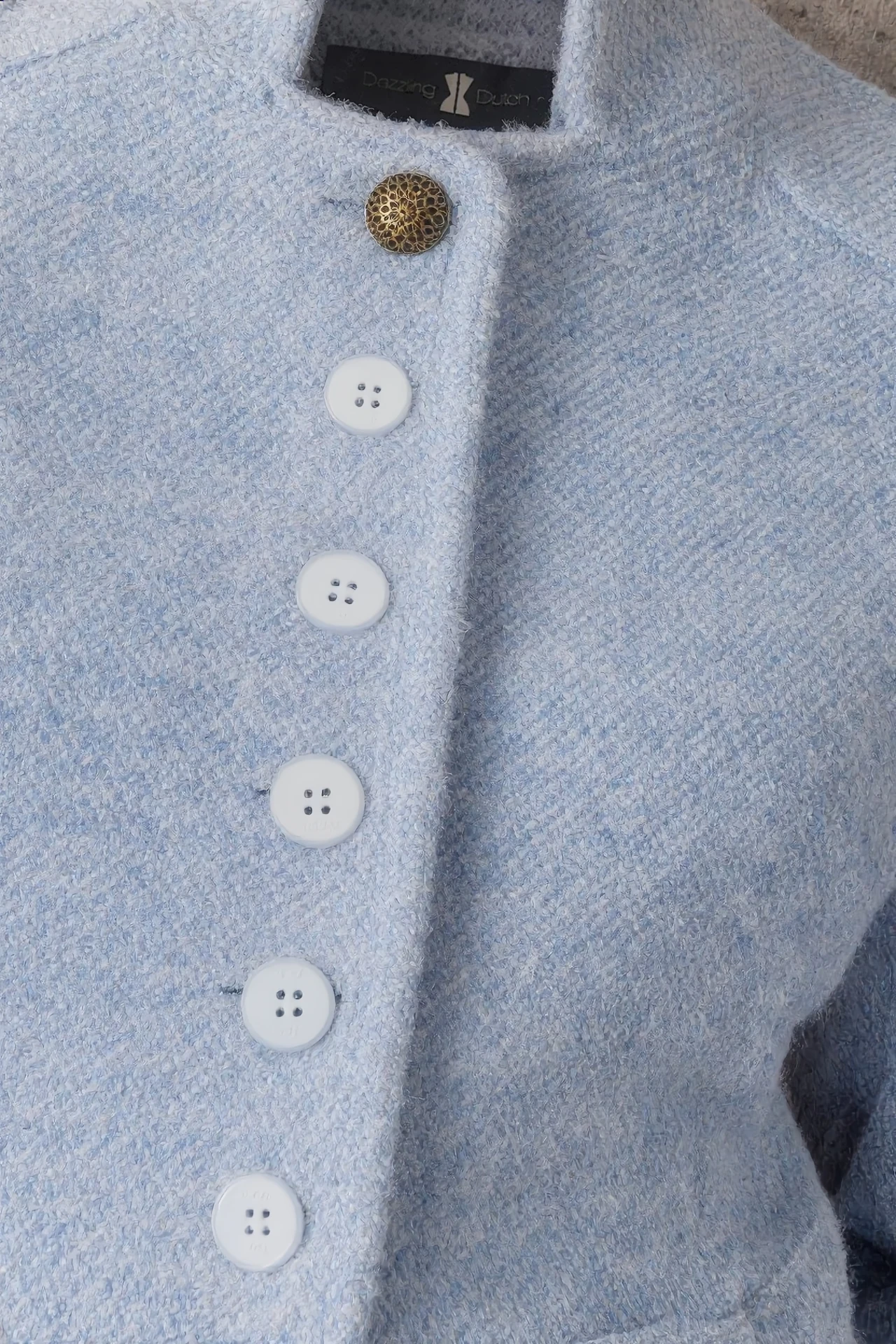 Close-up of the sky-blue jacket with buttons and Dazzling Dutch neck label