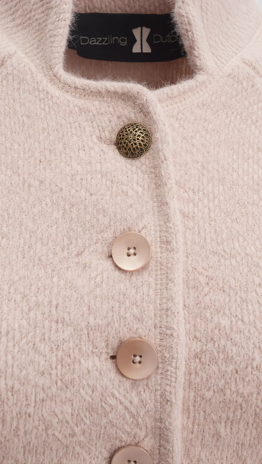 Close-up of the cream textured jacket with gold filigree button and Dazzling Dutch label