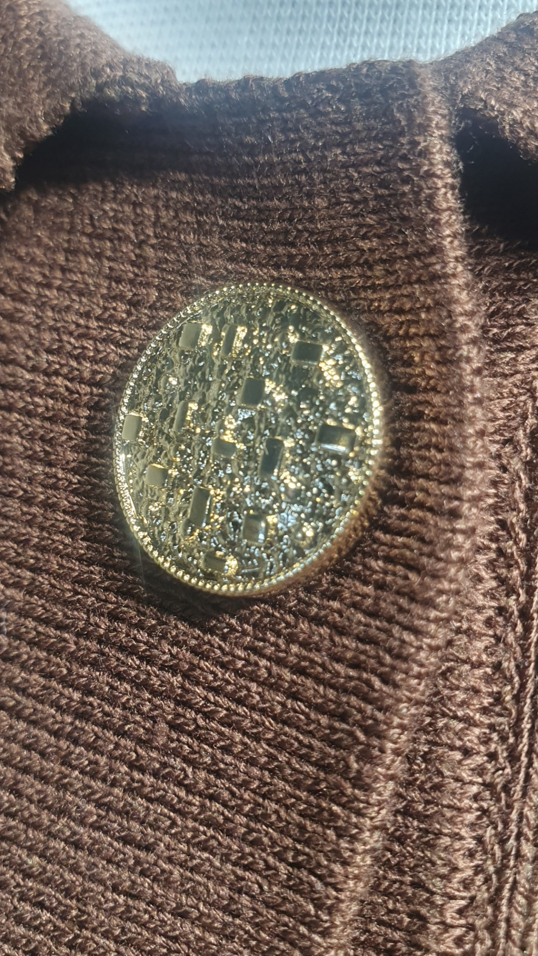 Close-up of the decorative gold button on the brown Demi jacket